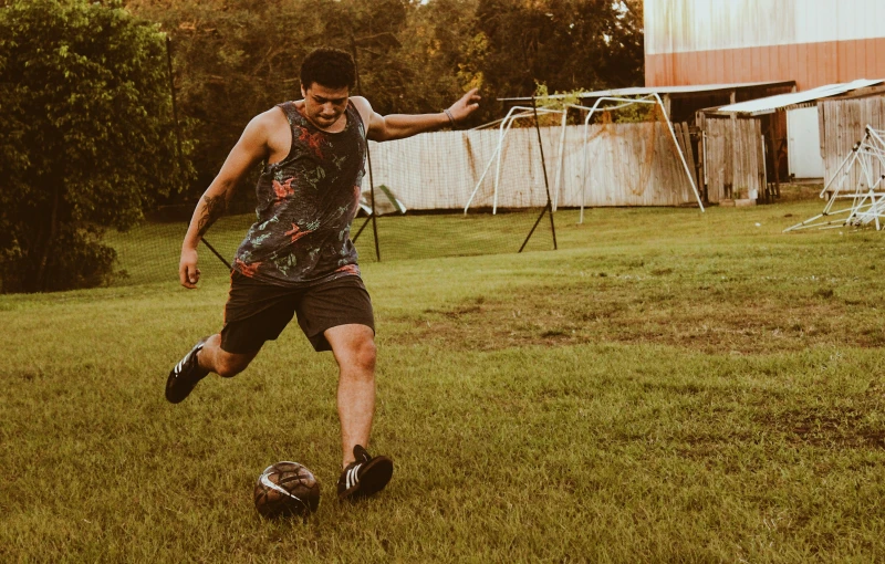 a man kicking a soccer ball across a lush green field