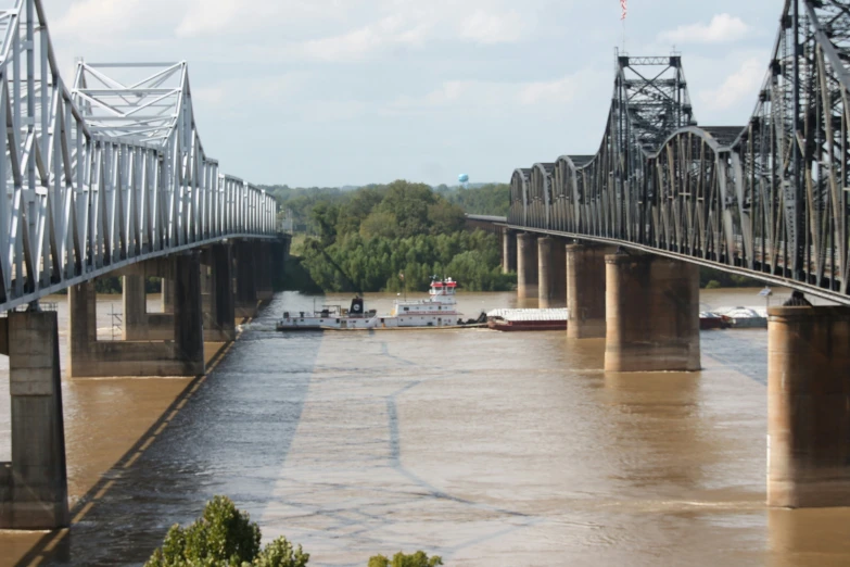 a river running under an old bridge that carries several boats