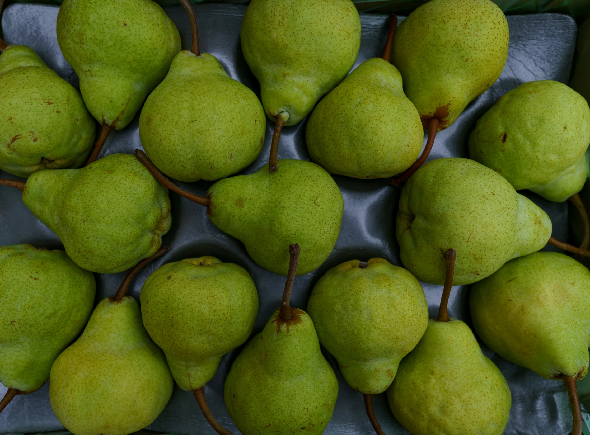 there are many green pears in a tray