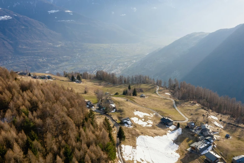 a mountain with lots of trees in the foreground and snow covered ground