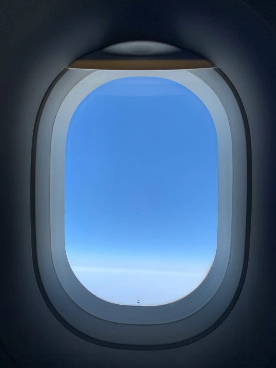 an airplane's windows shows the blue sky and clouds