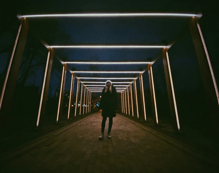 a woman walking down a dark pathway covered in lights