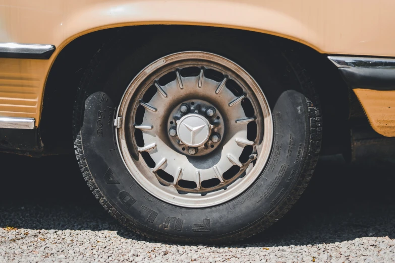 a close up of a flat tire on the back of an old yellow car