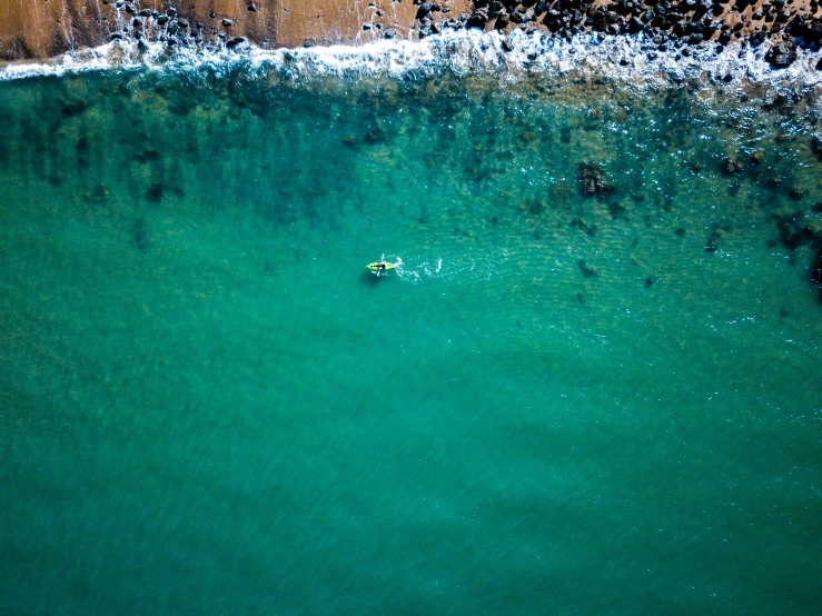 the person is paddling out on their surfboard in the clear blue water