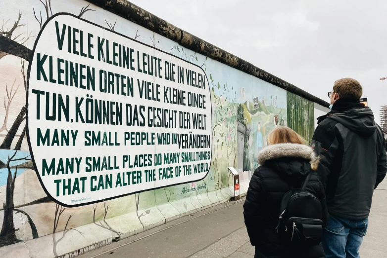 a man and woman standing in front of a wall that has graffiti on it