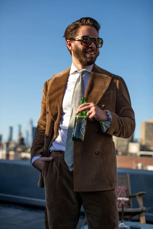 man in suit and tie holding beer and posing for po