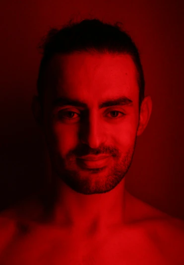 a man posing for a po with red light in the background