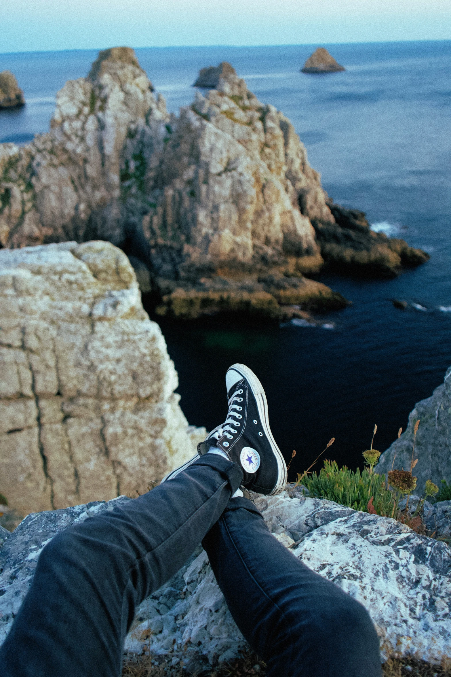 a person laying on top of a rock overlooking the ocean