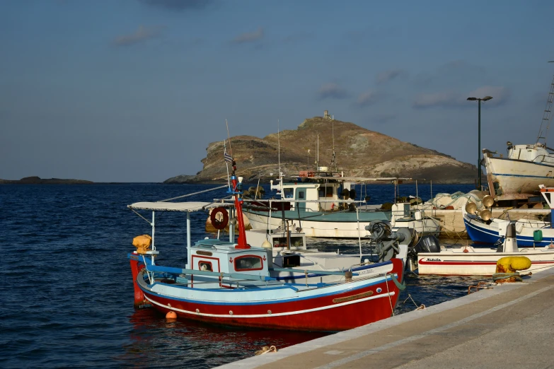 a few boats in the water next to a hill