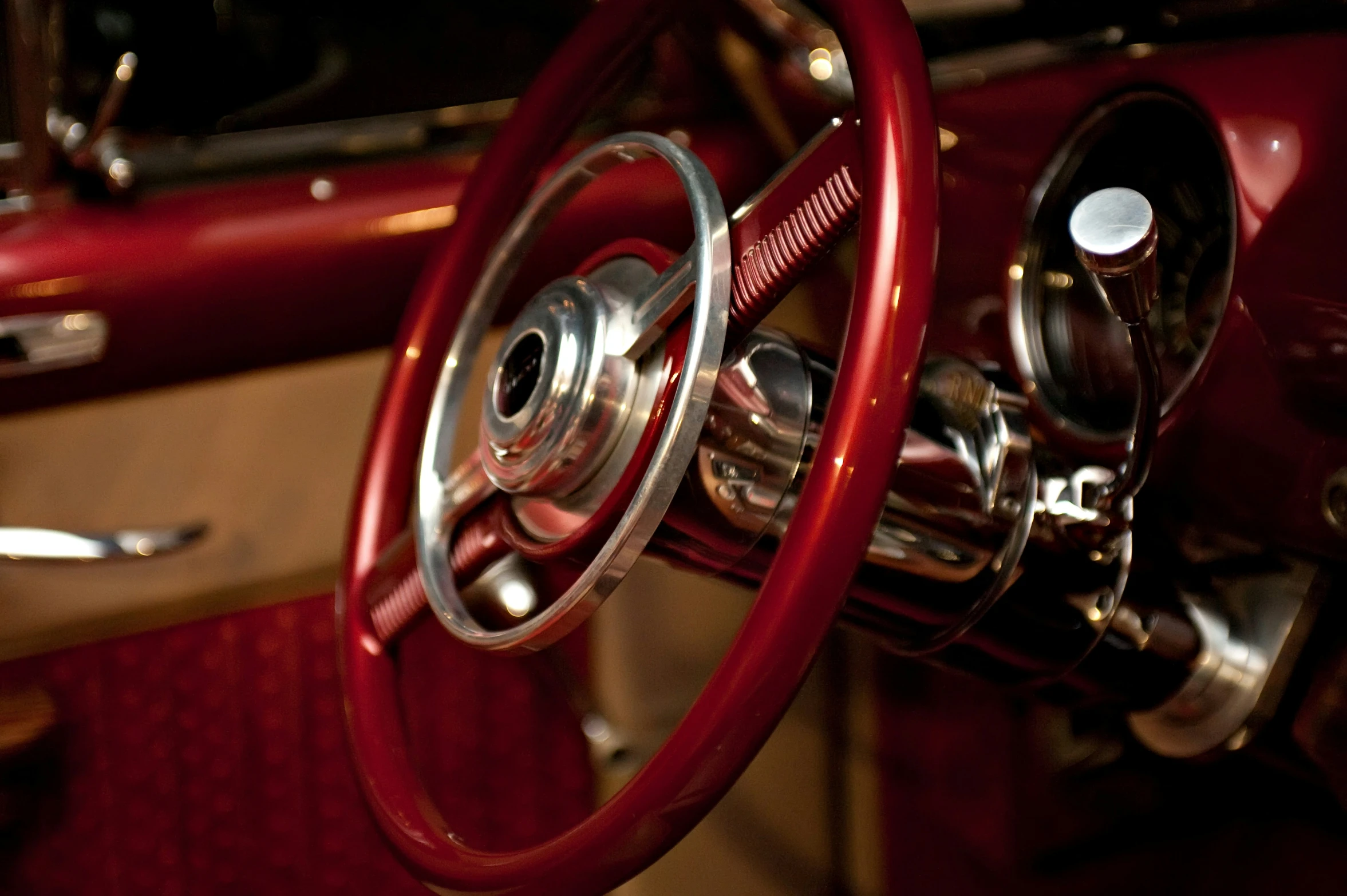 inside of an old car that has a nice red dash wheel and chrome trim