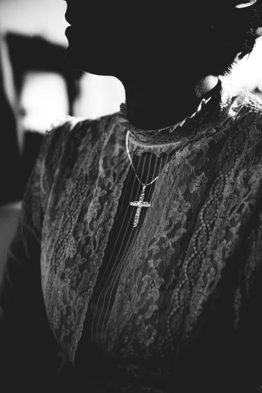 a woman's silhouette wearing a necklace and a cross pendant