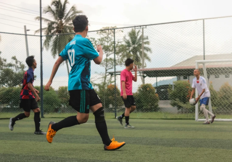 several soccer players playing on a field near the fence