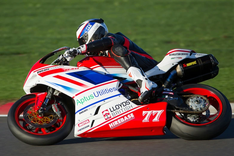 a motorcycle racer wearing an union jack livery is leaning into his turn on the track