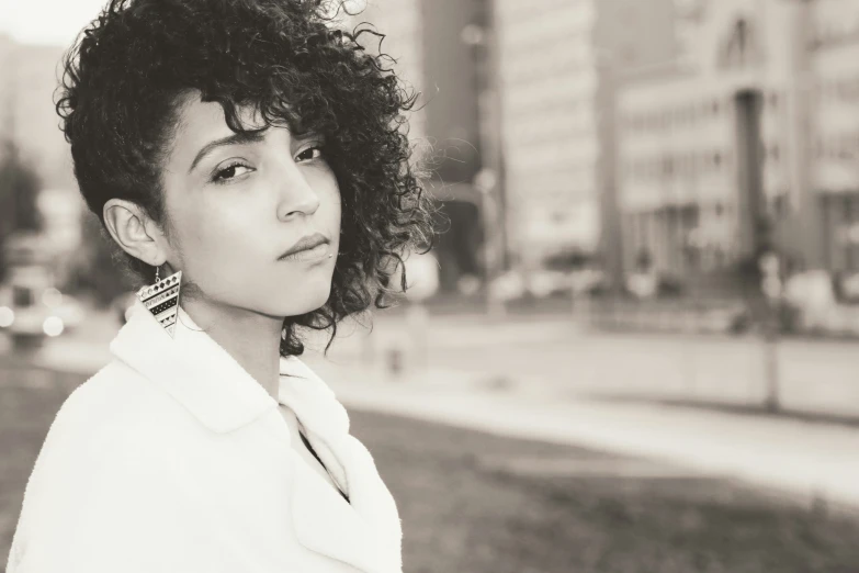 woman with short curly hair wearing white coat on grassy area