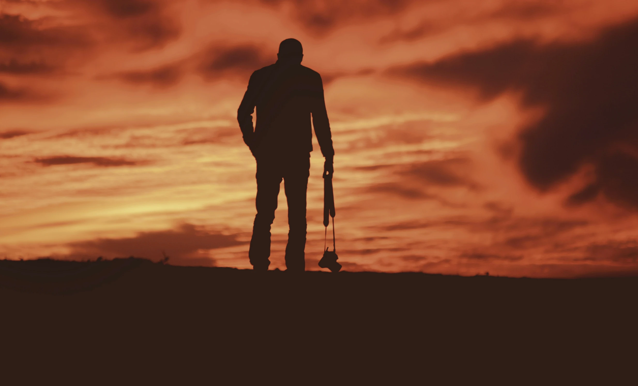 a silhouetted person standing with a golf club under a dramatic sky