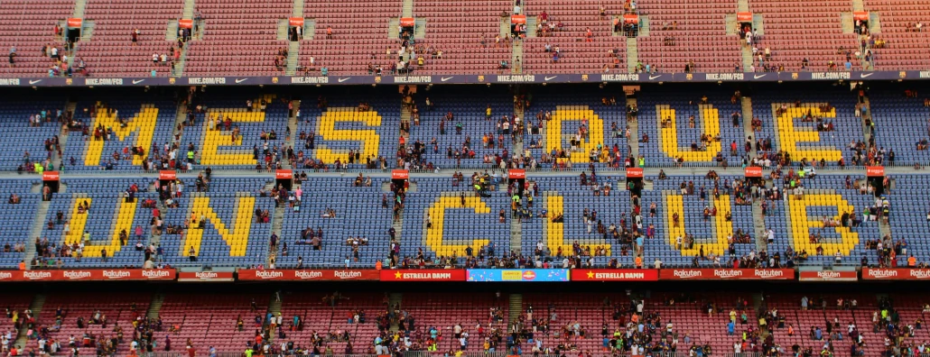 people hang from the stands in an arena to form a line in memory of their athletes