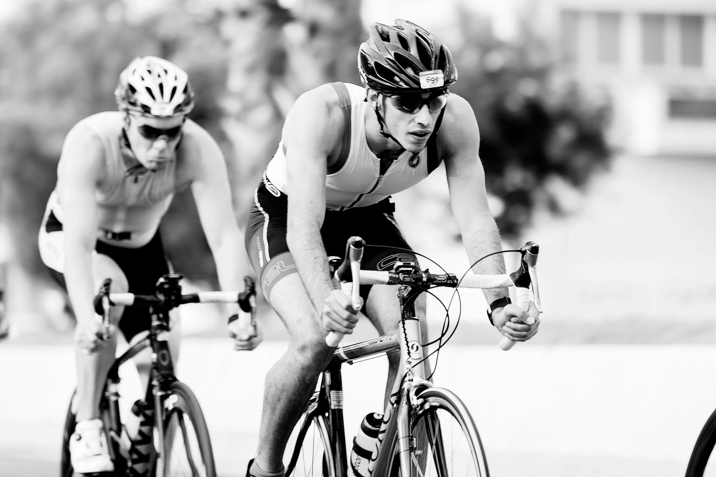 two cyclists in helmets are racing down a street