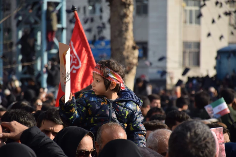 a crowd of people marching down the street with flags and banners