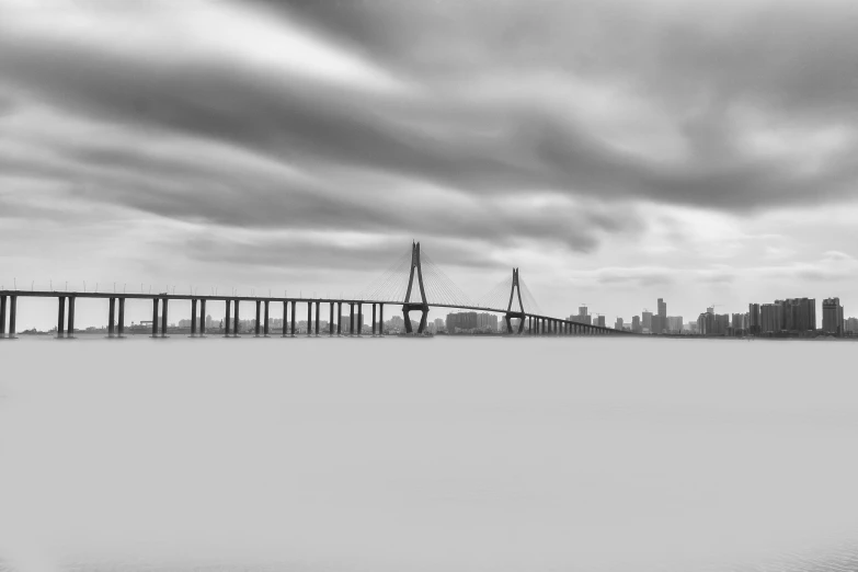 a long bridge sitting above the ocean under a cloudy sky