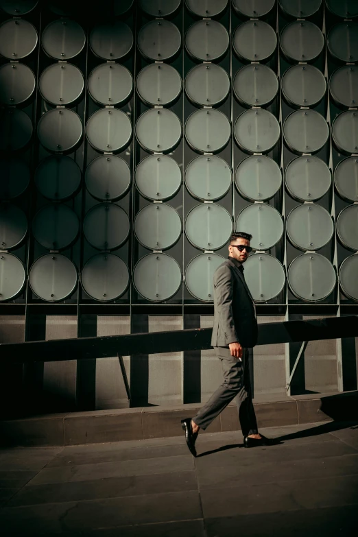 a man walks down a street past a building with round mirrors