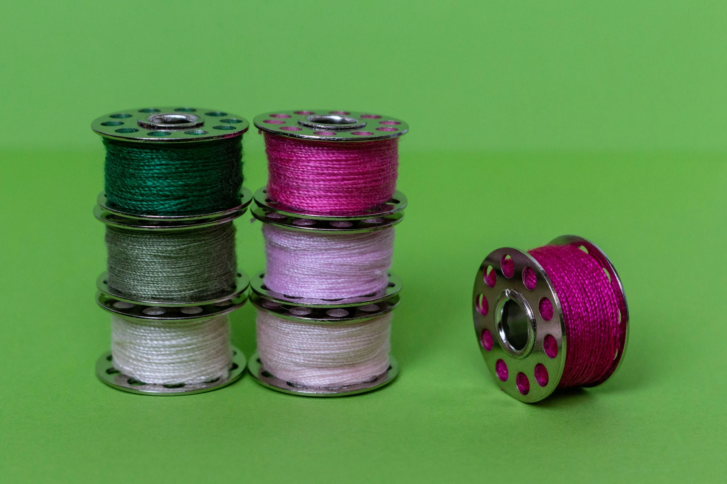 four spooles of thread on a green background