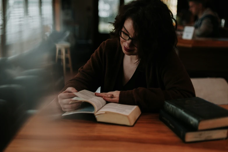 a woman is reading a book while sitting at a table