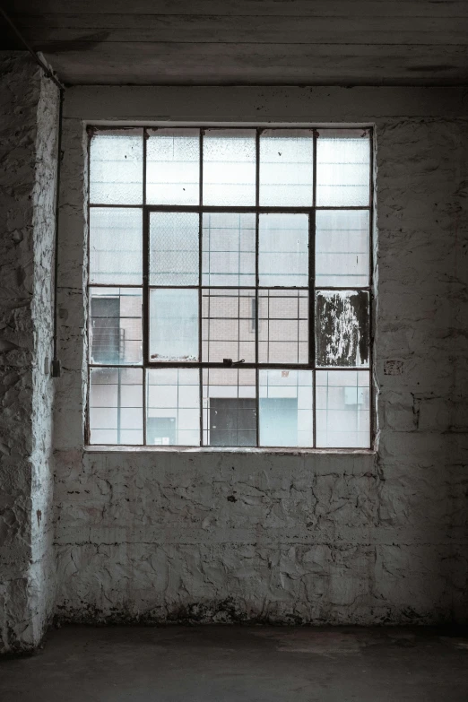 a brick wall with a square window, partially closed and surrounded by squares of squares, on which is a tree