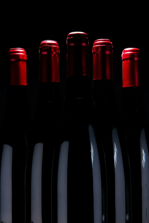 several bottle of red wine on a dark table