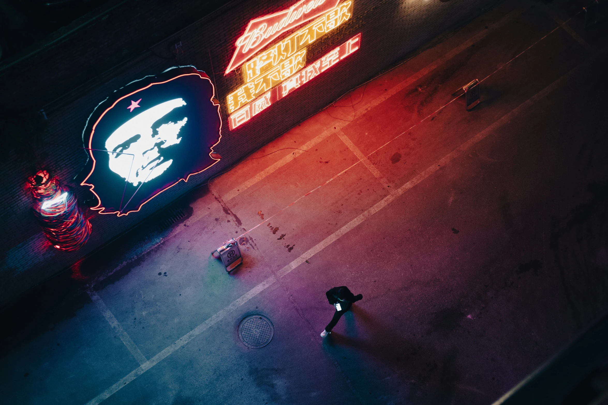 a woman walking down the street with an umbrella next to a neon sign