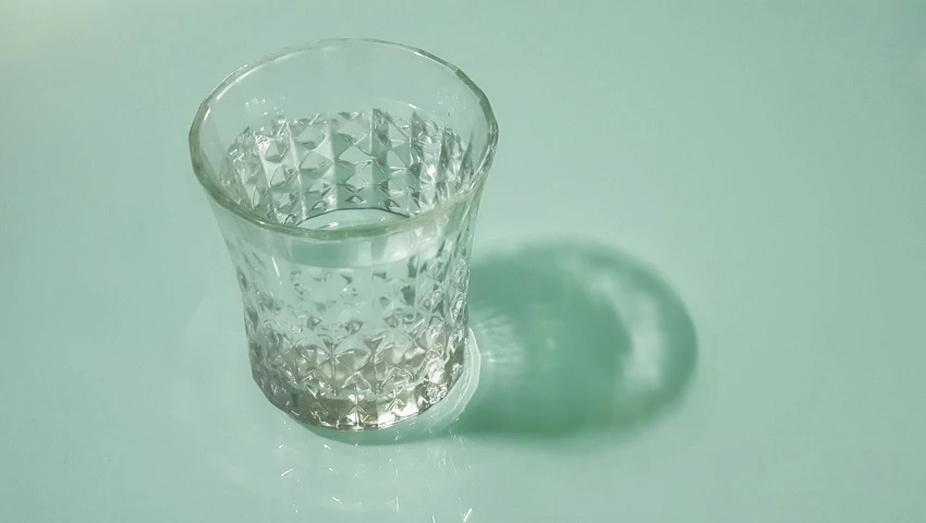 a glass on a table with a shadow