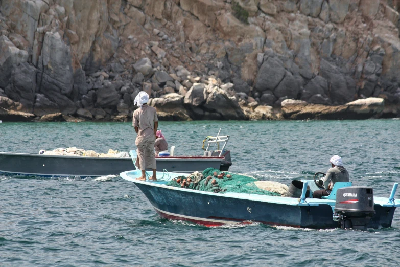 two men in the back of a small blue boat