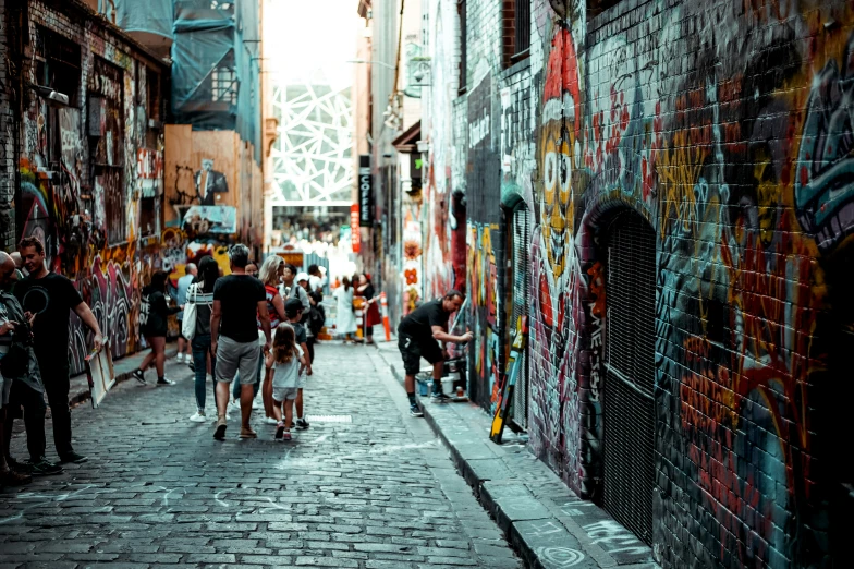 people walk down an alleyway in a city with graffiti on the walls