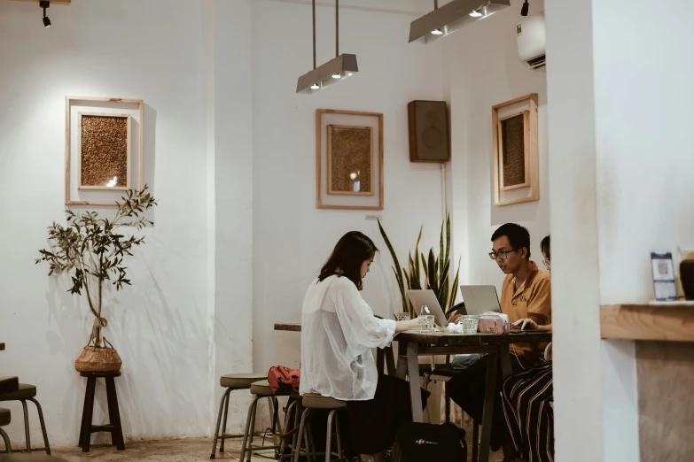 a man and woman sit at a table with their laptop