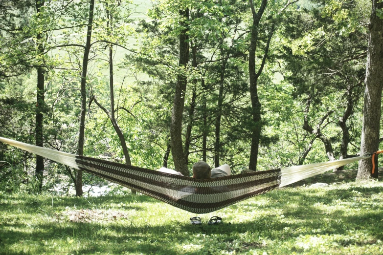 a man that is laying in a hammock