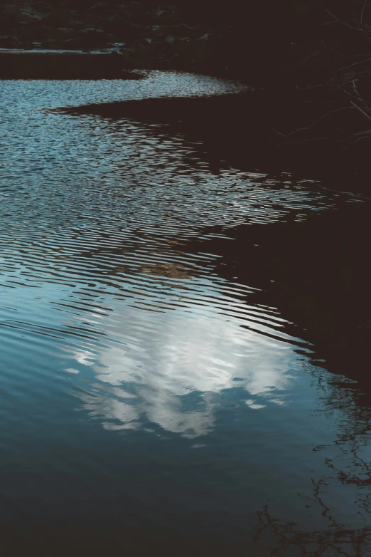 clouds are reflected in the water on a calm day