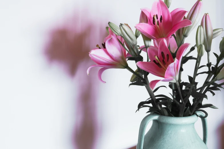 pink lilies are in a blue vase on the table