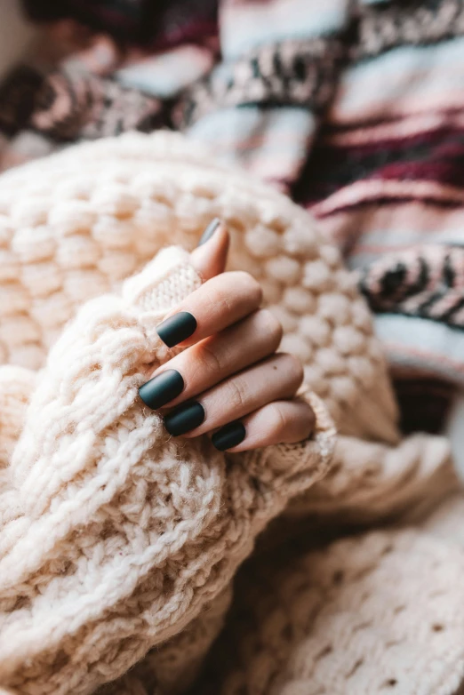 woman's hands with a black manicure holding a scarf