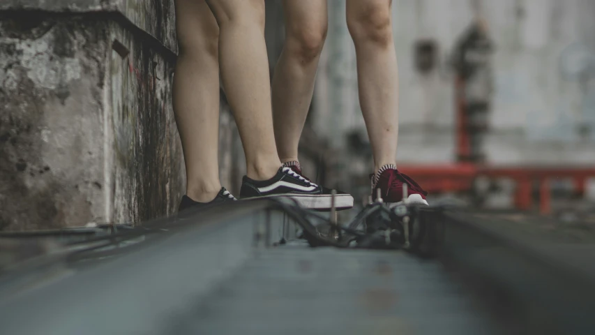 legs wearing black and white sneakers while standing on a railing