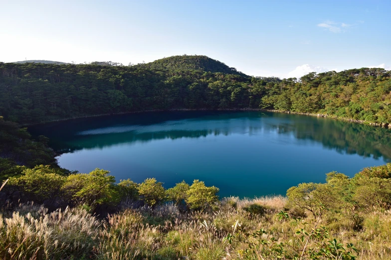 a blue lake surrounded by trees on a sunny day