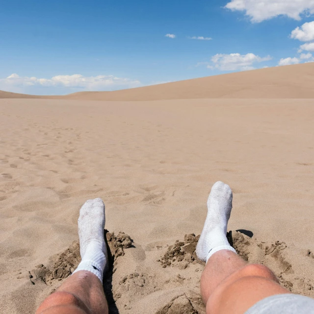 someone has their feet in the sand with their legs up