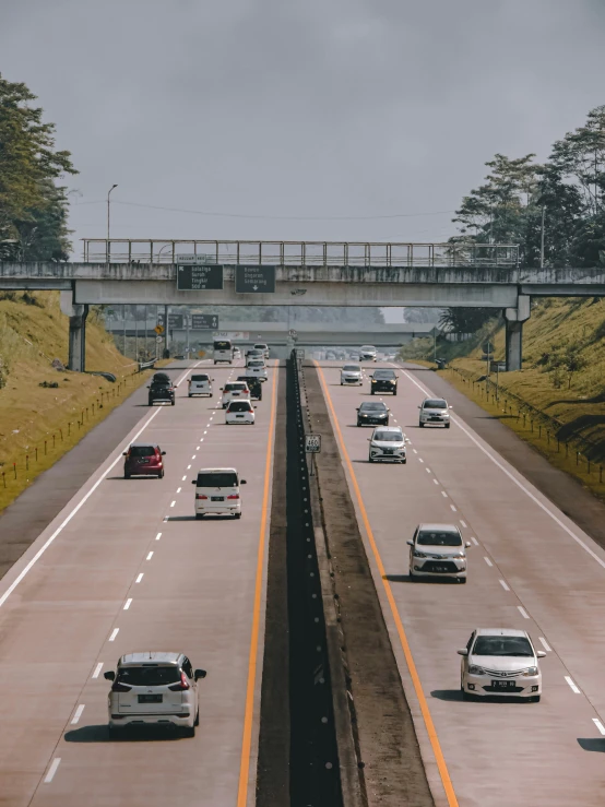 many cars and trucks travel on a road with yellow lines