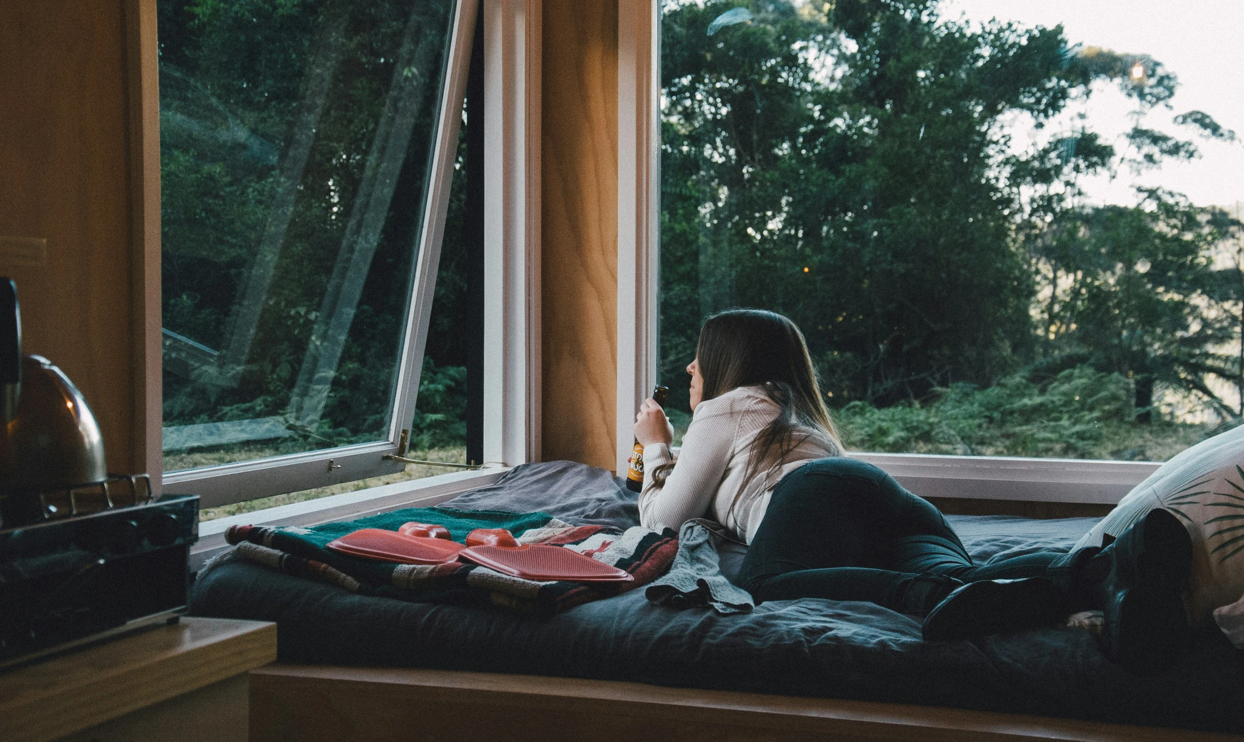 a girl sitting in bed while looking out a window