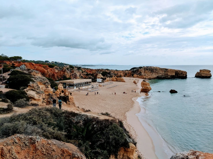 several people are walking along a beach next to the ocean