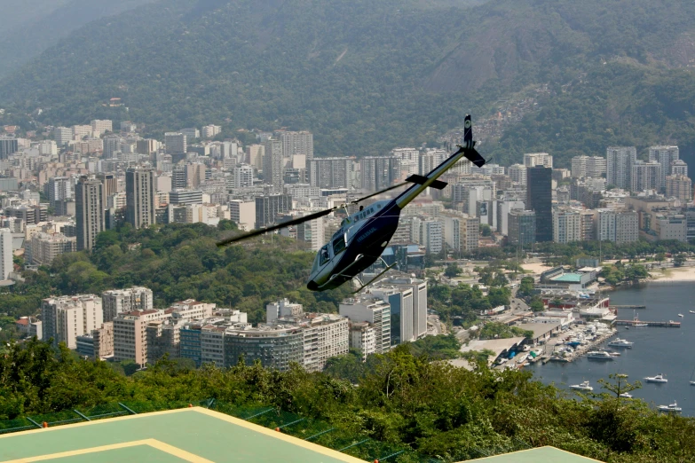 helicopter is flying over the city near a bay