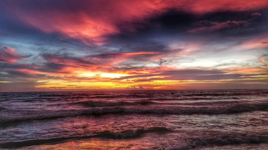 the sun is setting over the ocean with very colorful clouds