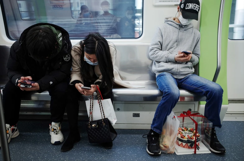 people sitting on the subway with their phones