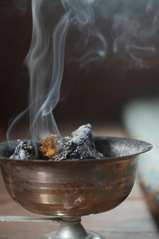 steaming tobacco on a pewter dish with smoke and wood
