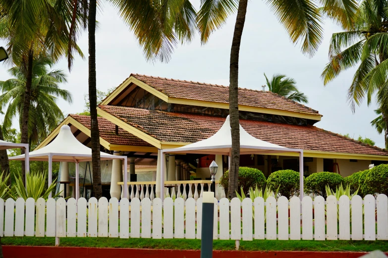 white fence and trees behind a large house