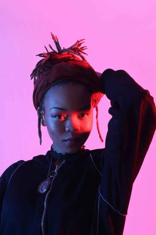 woman in black dress with feather headscarf against a pink background