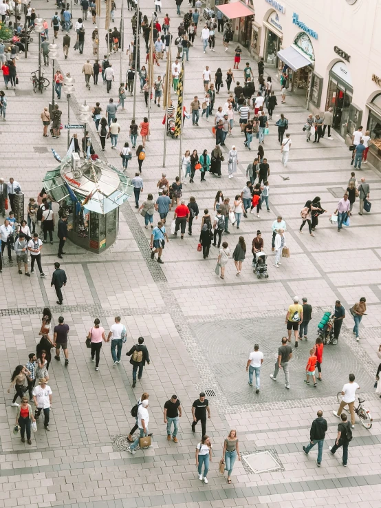 many people walking along and a large food cart in the middle of an empty plaza